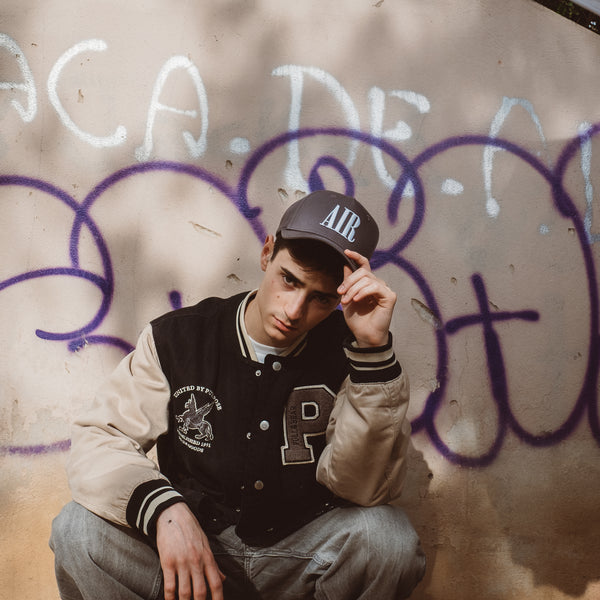 Ung mand i sort baseball cap med AIR logo foran graffiti væg