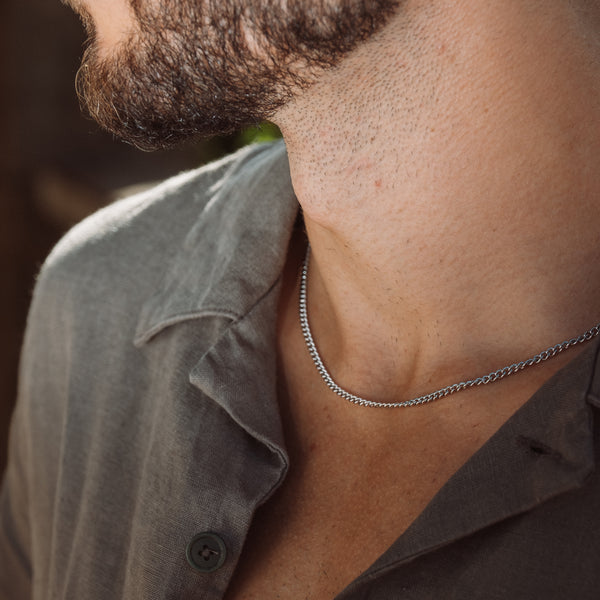 Mand bærer sølvfarvet curb chain halskæde