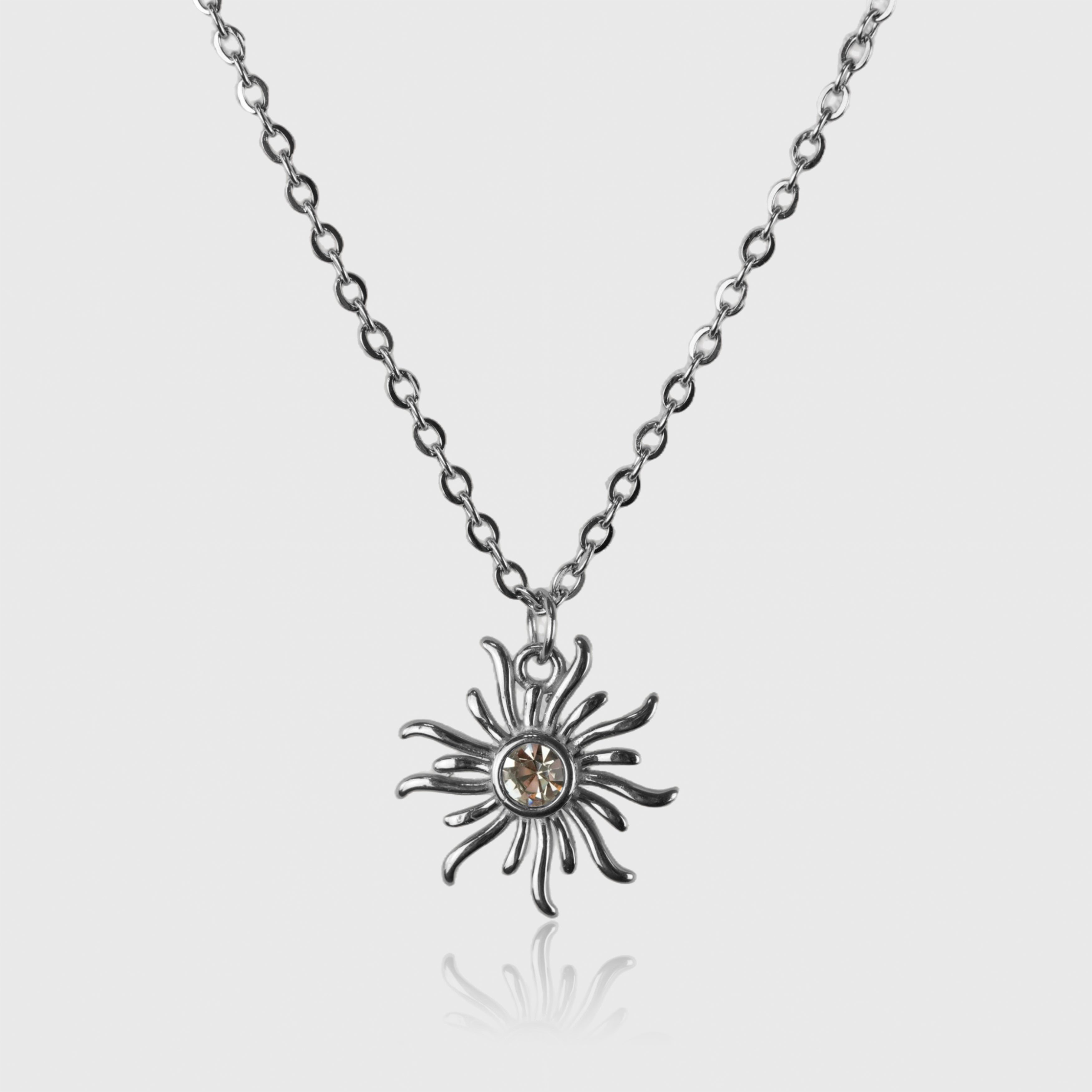 Sølvfarvet halskæde med solformet vedhæng og guldtonekrystal