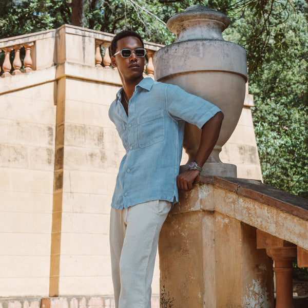 Mand iført blå kortærmet skjorte og solbriller ved stenskulptur