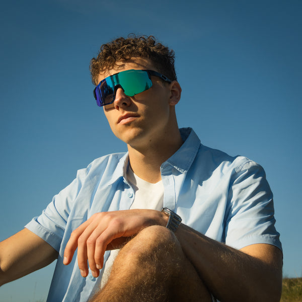 Mand bærer Noire Murky sportsbriller i petrol med blågrønne spejlglas udendørs