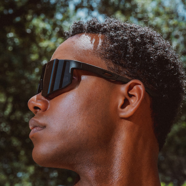 Noire Blackout sportsbriller i sort med futuristisk design båret udendørs i profil