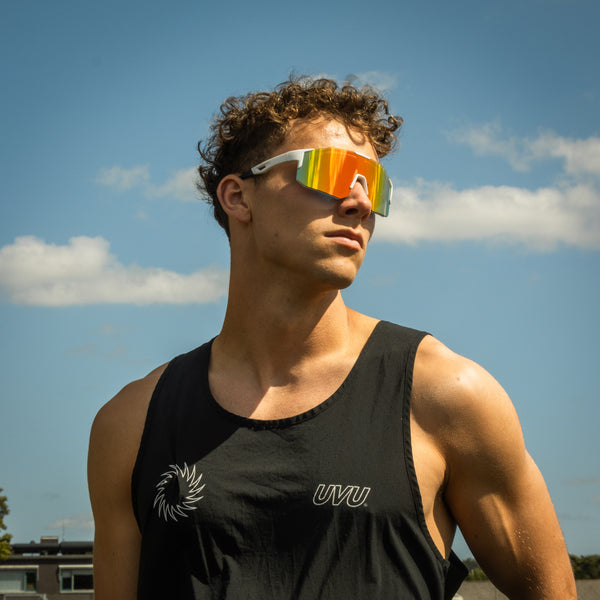 Sportsbriller med hvid stel og orange spejlglas i udendørs sollys