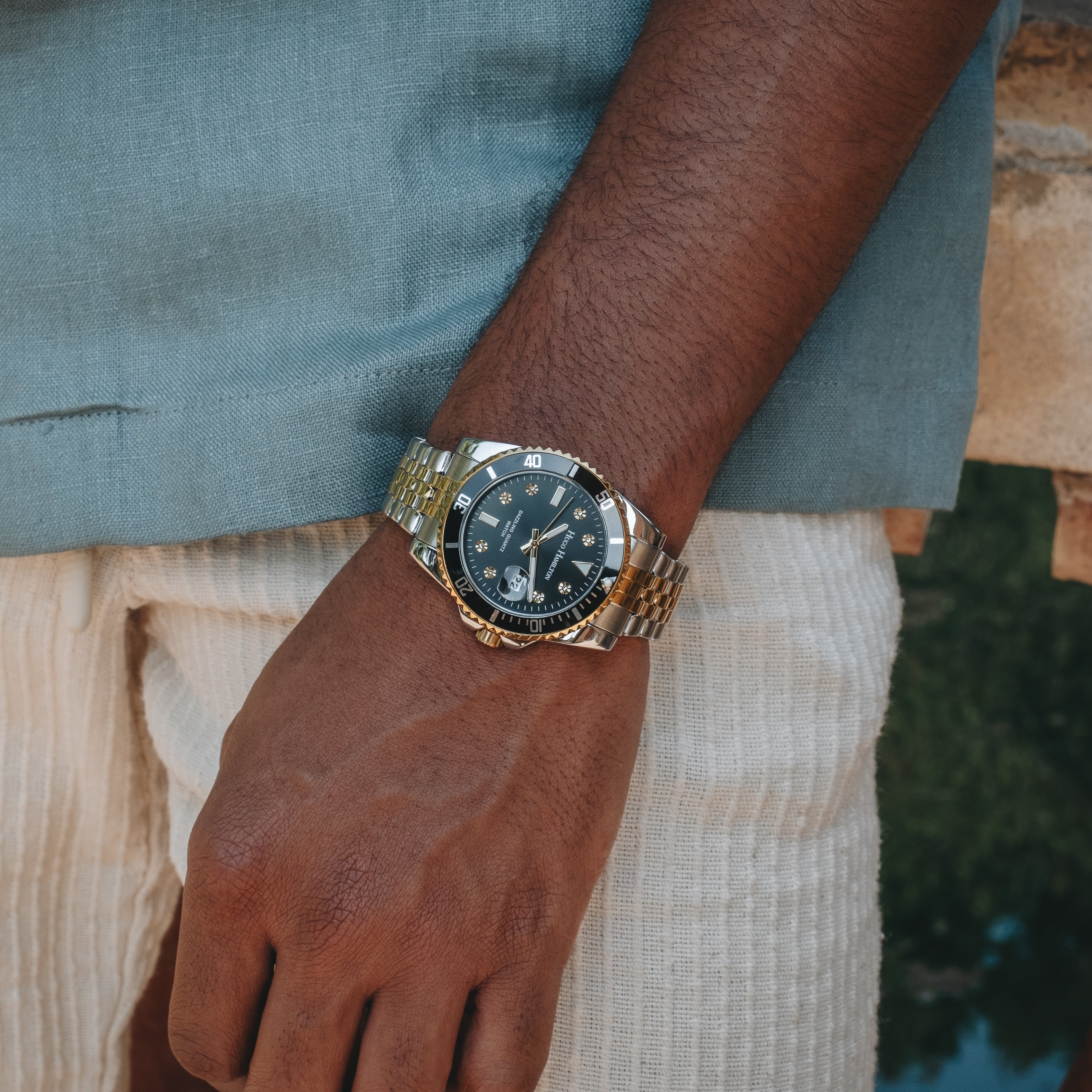 Guldfarvet armbåndsur med sort urskive på håndled