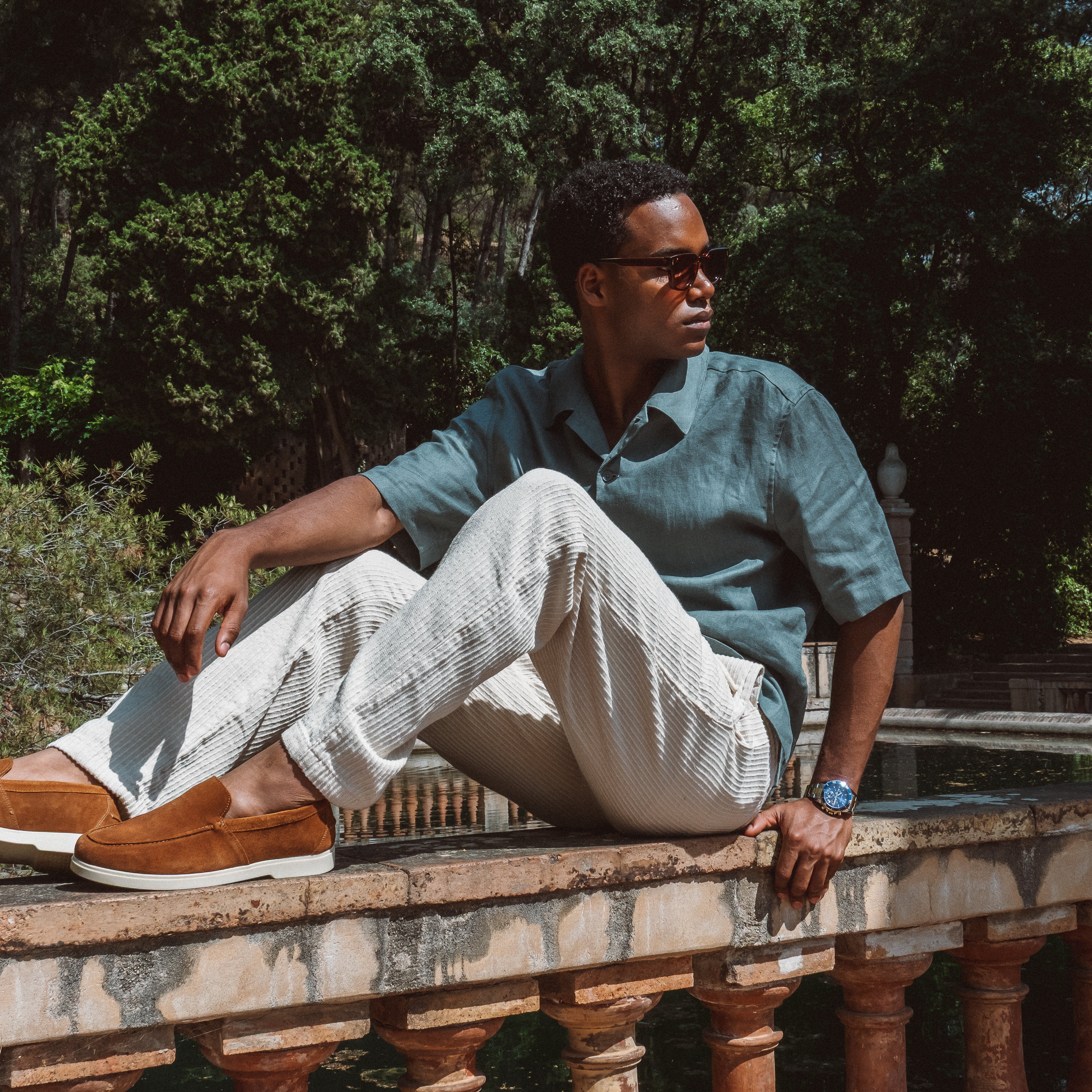 Mand i turkis skjorte og stribede bukser med brune loafers