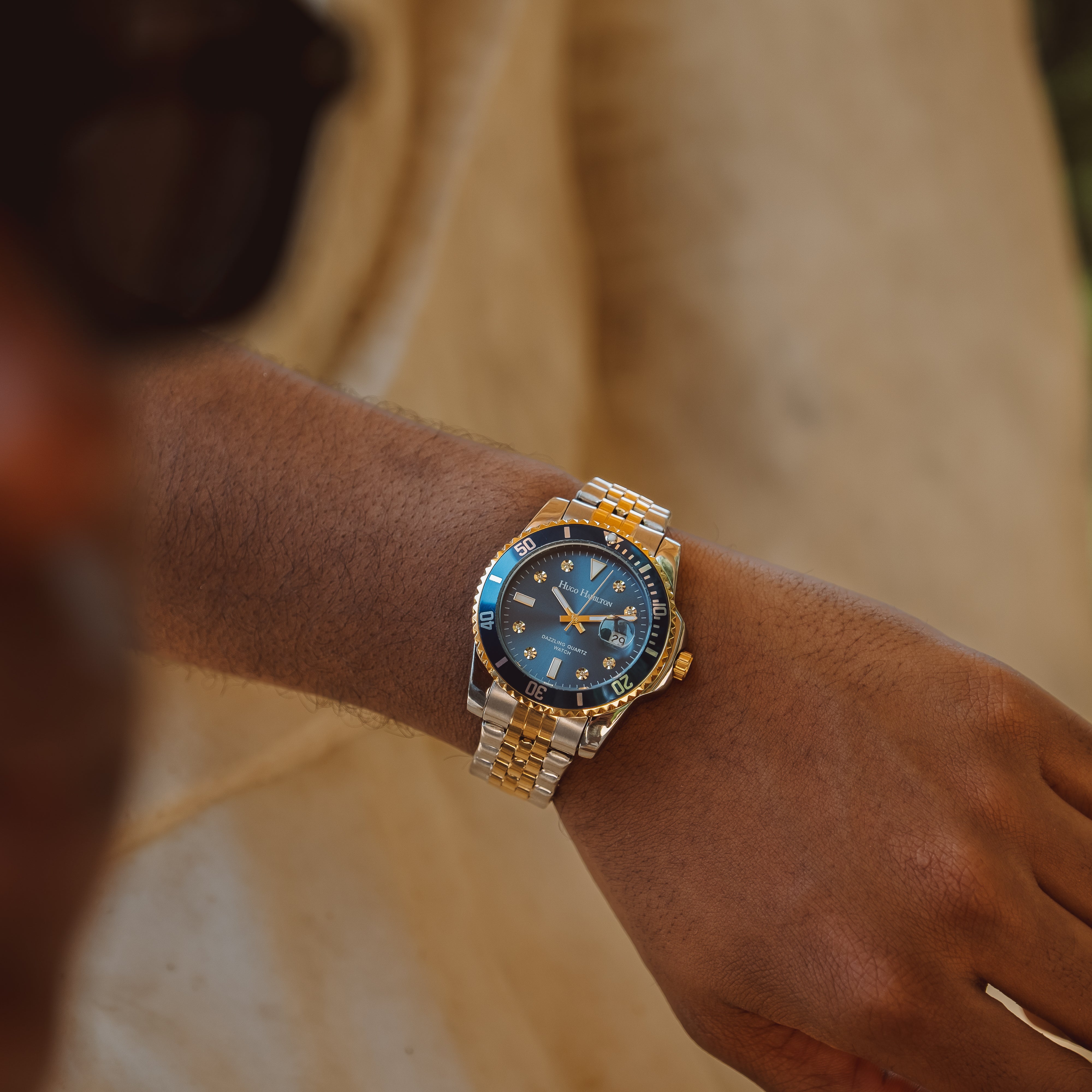 Armbåndsur med blå urskive og tofarvet stållænke på håndled