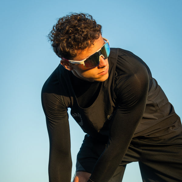 Mand i sort sportstøj bærer Noire Frost sportsbriller i hvid med blå spejlglas