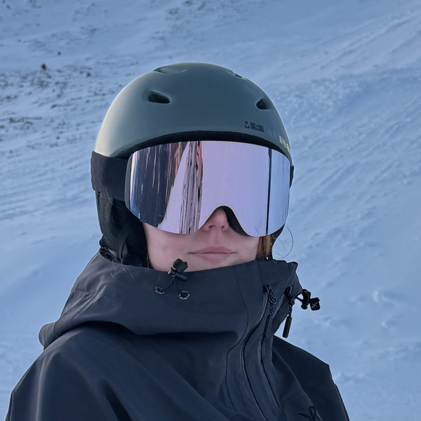 Skibriller med rosa spejlglas og hvid hjelm på snedækket piste