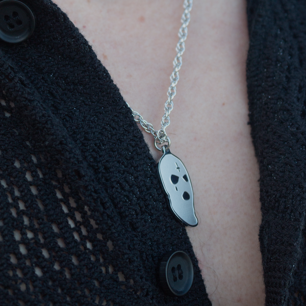 Sølvfarvet halskæde med spøgelsesvedhæng på sort tøj