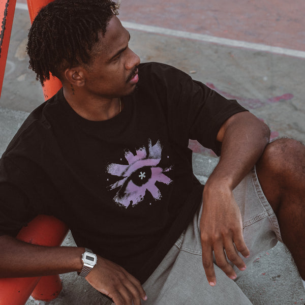 Mand iført sort Purple Eye Tee oversized t-shirt fra Fadeless med lilla øje-print