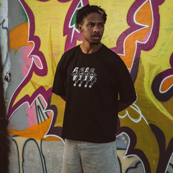 Mand i sort oversized Chicks Tee foran farverig graffiti væg