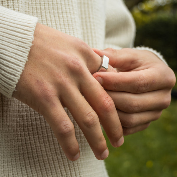 Sølvfarvet ring med hvid porcelænsdetalje på finger