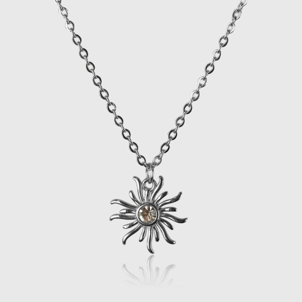 Sølvfarvet halskæde med solformet vedhæng og guldtonekrystal