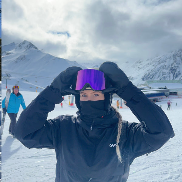 Kvinde justerer Glaciér skibriller med lilla linser på snedækket piste