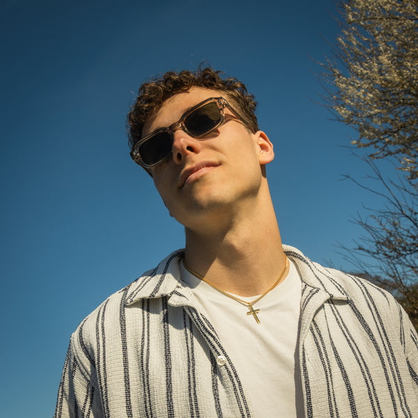 Mand med Sean Straw solbriller i transparent grøn mod blå himmel