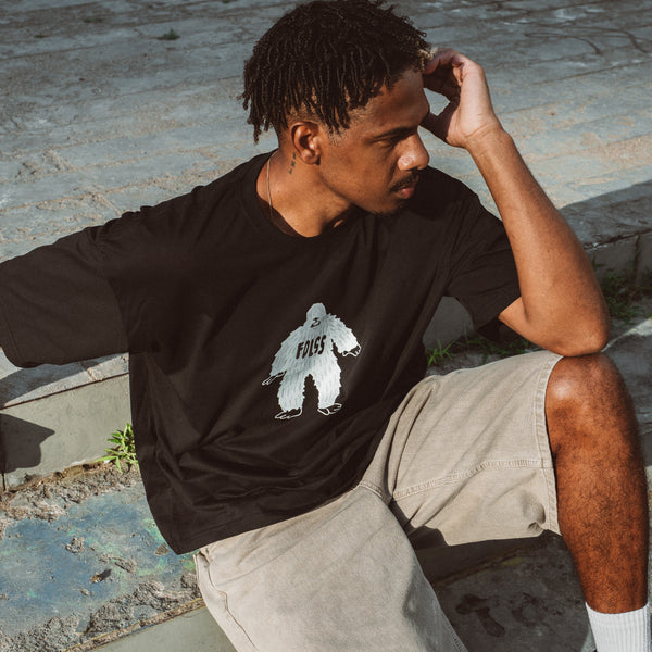 Mand iført sort Ray Tee t-shirt med hvidt bjørneprint og beige shorts