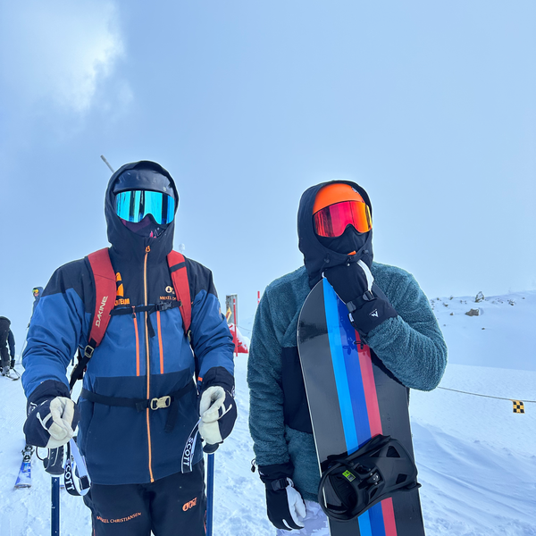 To skiløbere med Glaciér skibriller i blå og orange spejlglas på snedækket bjerg